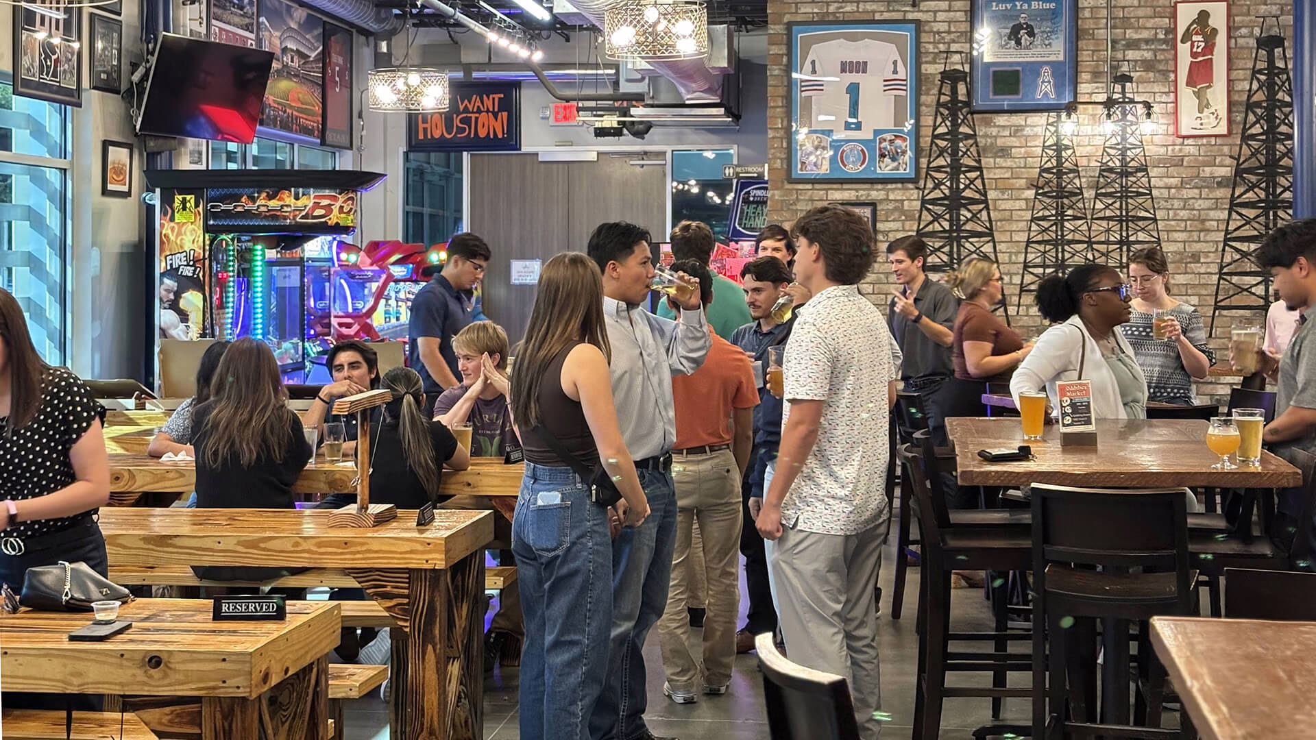 A group of employees enjoying conversation with a glass of beer at a Houston corporate event venue.